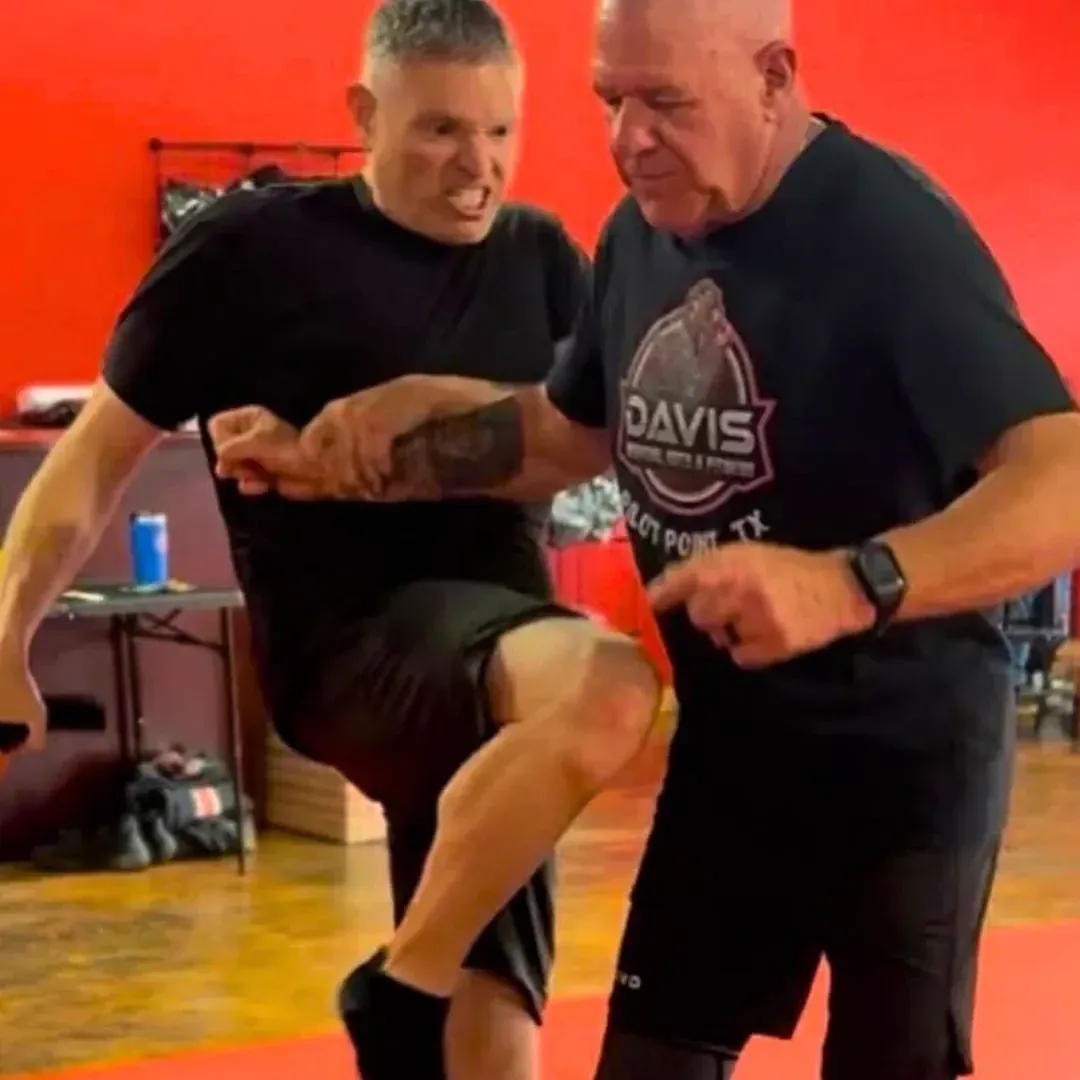Knee-strike self-defense drill against the red wall at Davis Martial Arts & Fitness in Pilot Point, TX
