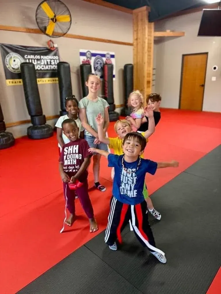 Group of summer camp kids posing playfully on the mats at Davis Martial Arts & Fitness in Pilot Point, TX