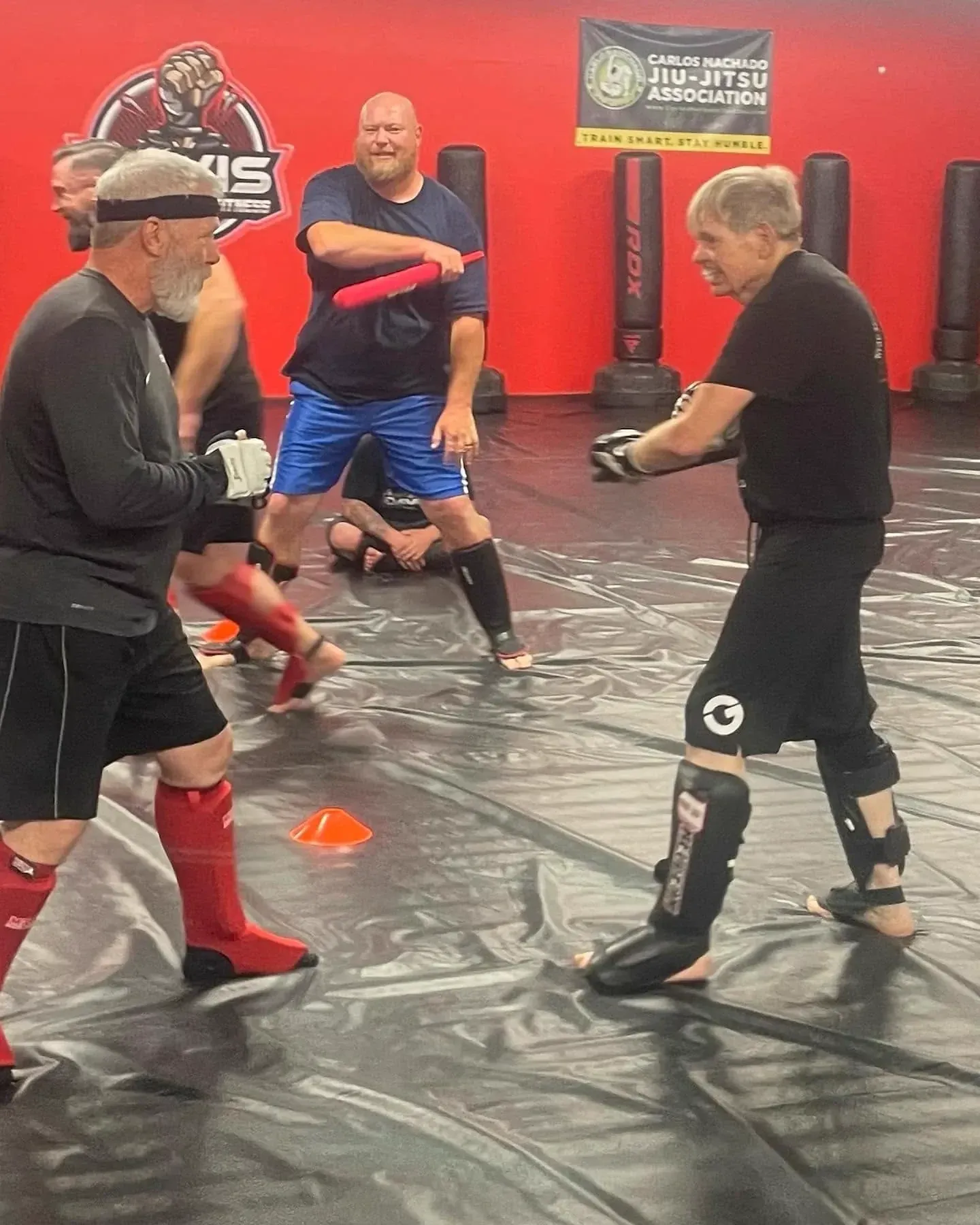 Striker landing a high kick on a pad by the Carlos Machado banner at Davis Martial Arts & Fitness in Pilot Point, TX