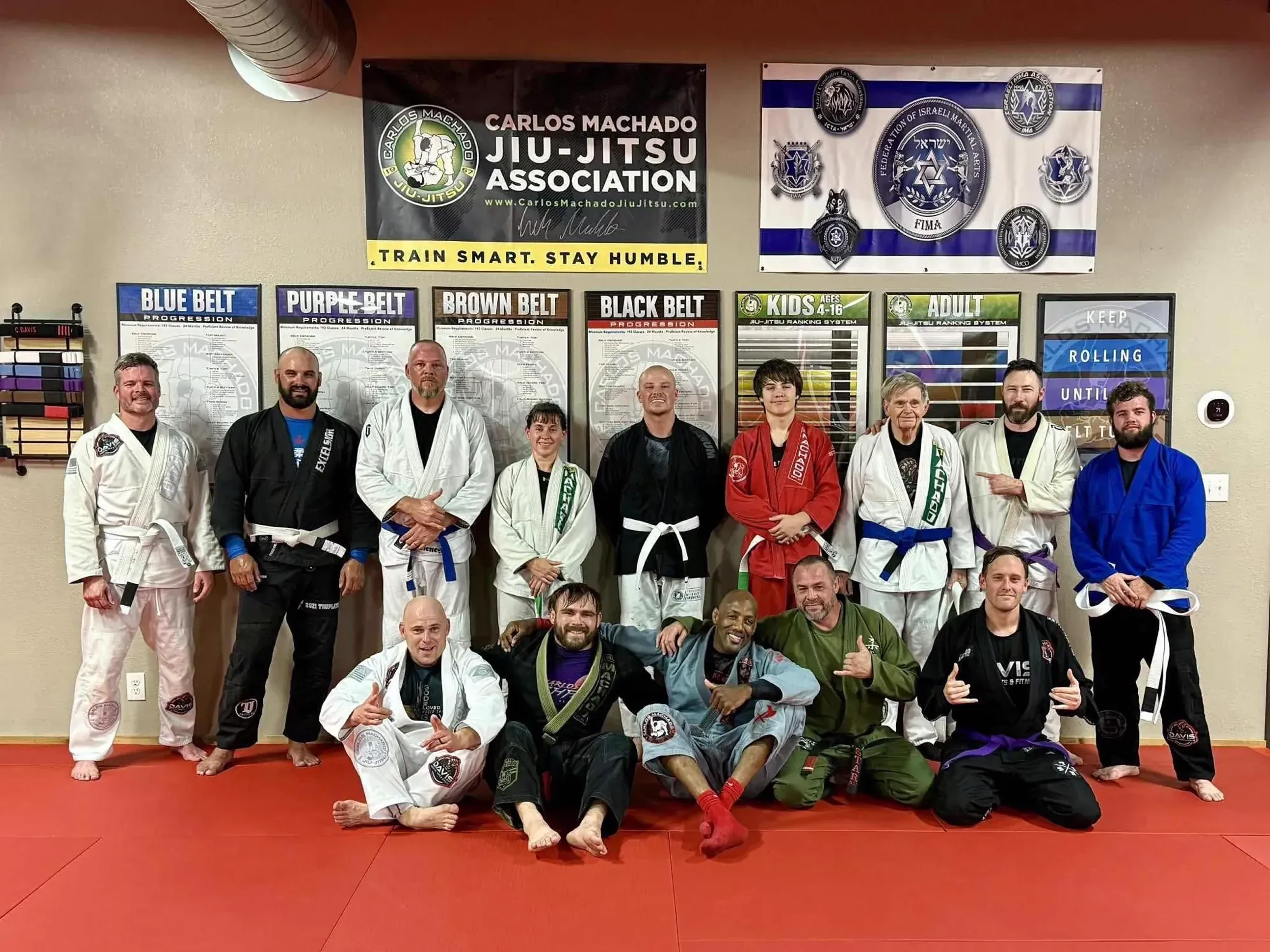 Large adult Brazilian Jiu-Jitsu class group photo by the Carlos Machado banner at Davis Martial Arts & Fitness in Pilot Point, TX