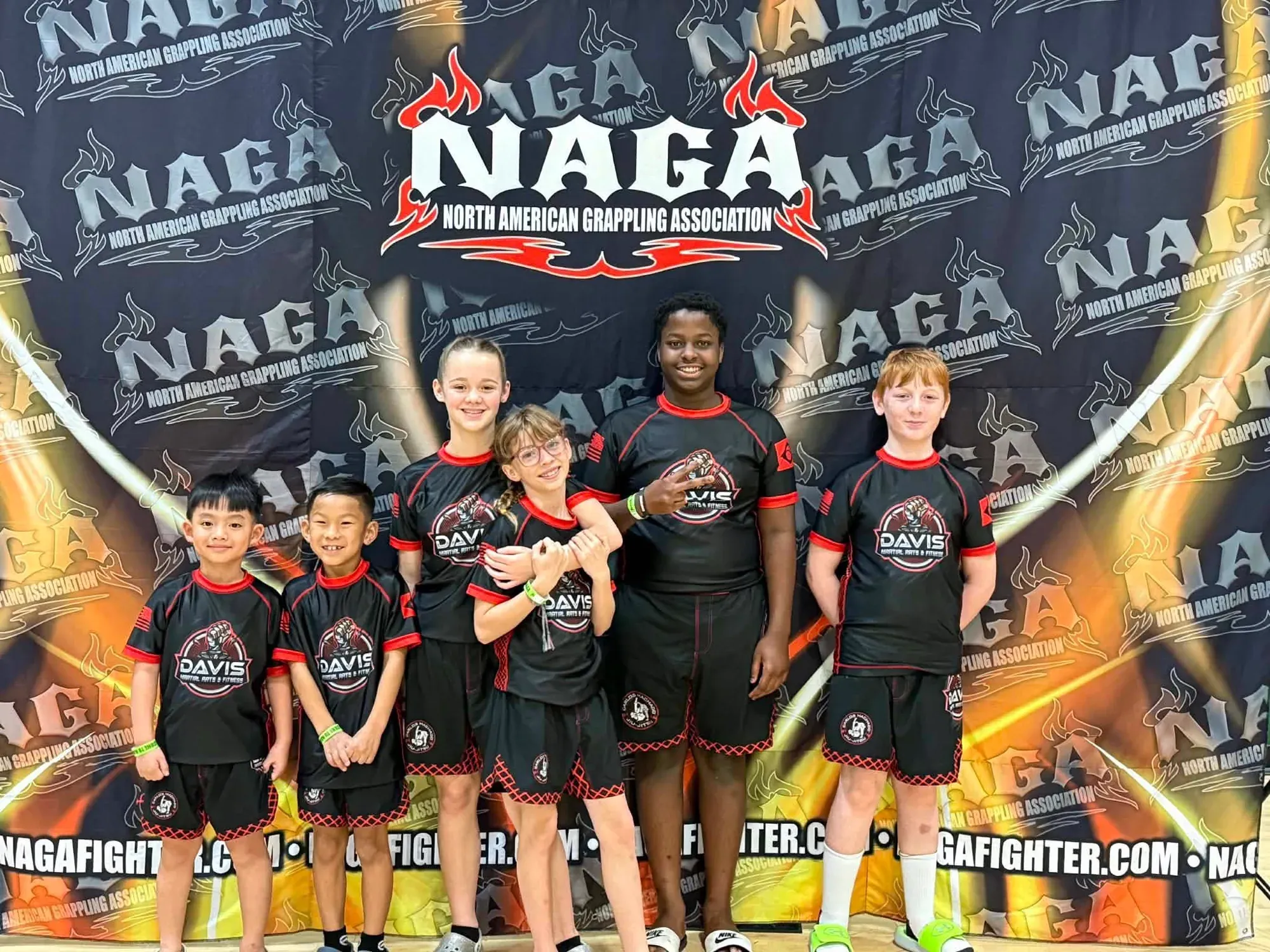 Six young students in Davis Martial Arts & Fitness team rash guards at a North American Grappling Association tournament