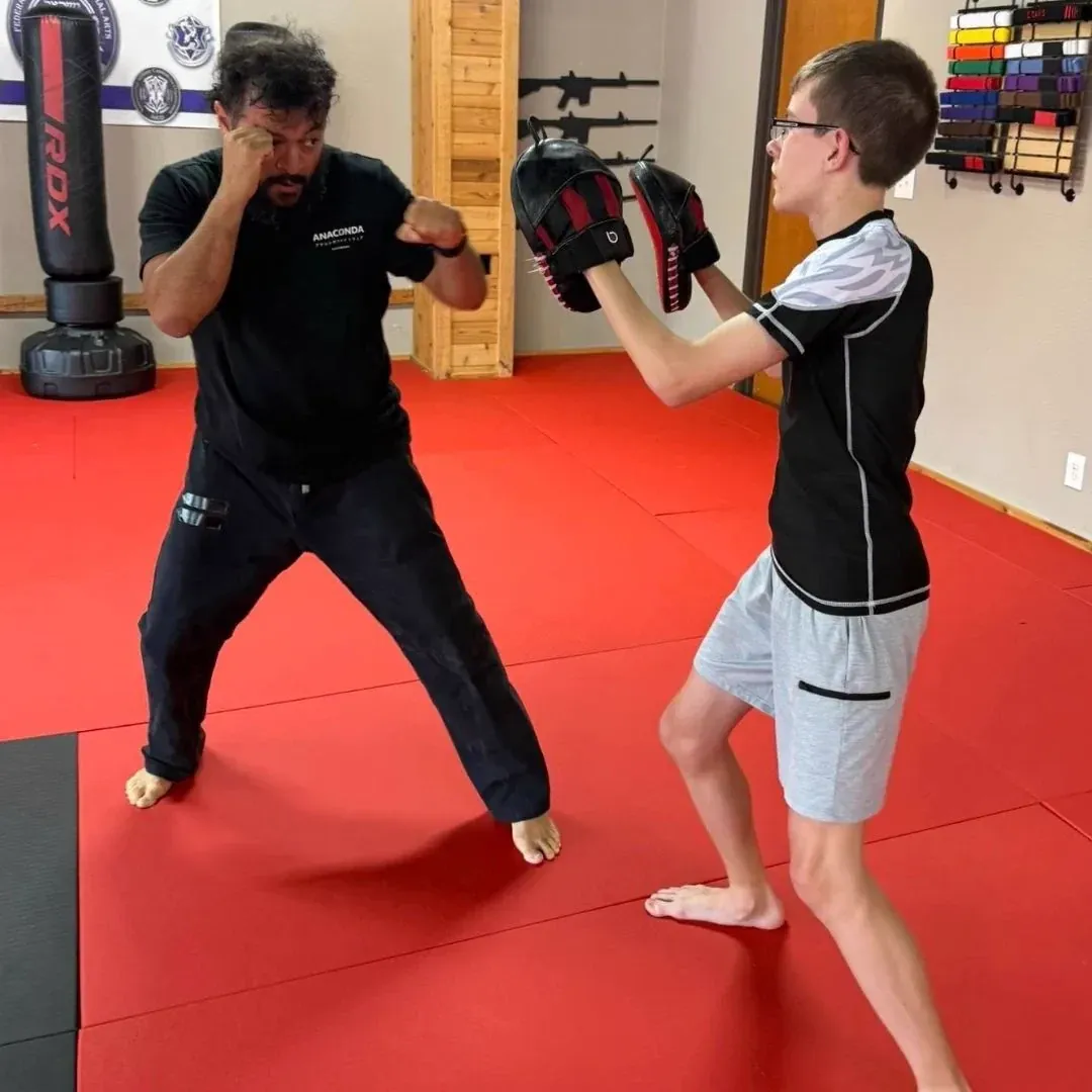 Coach holding focus mitts for a striker at Davis Martial Arts & Fitness in Pilot Point, TX