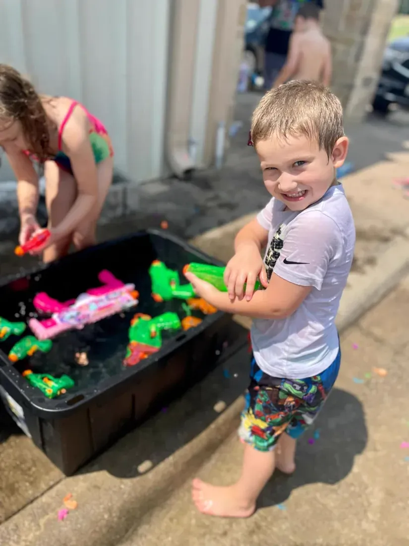 A summer camp boy loading up at a bin of water toys outside Davis Martial Arts & Fitness in Pilot Point, TX