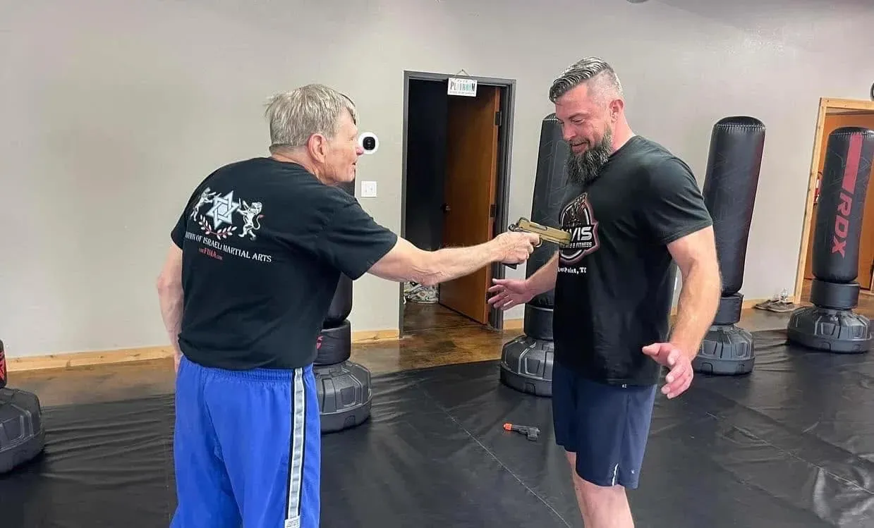 Two men drilling a Krav Maga handgun-disarm self-defense technique at Davis Martial Arts & Fitness in Pilot Point, TX