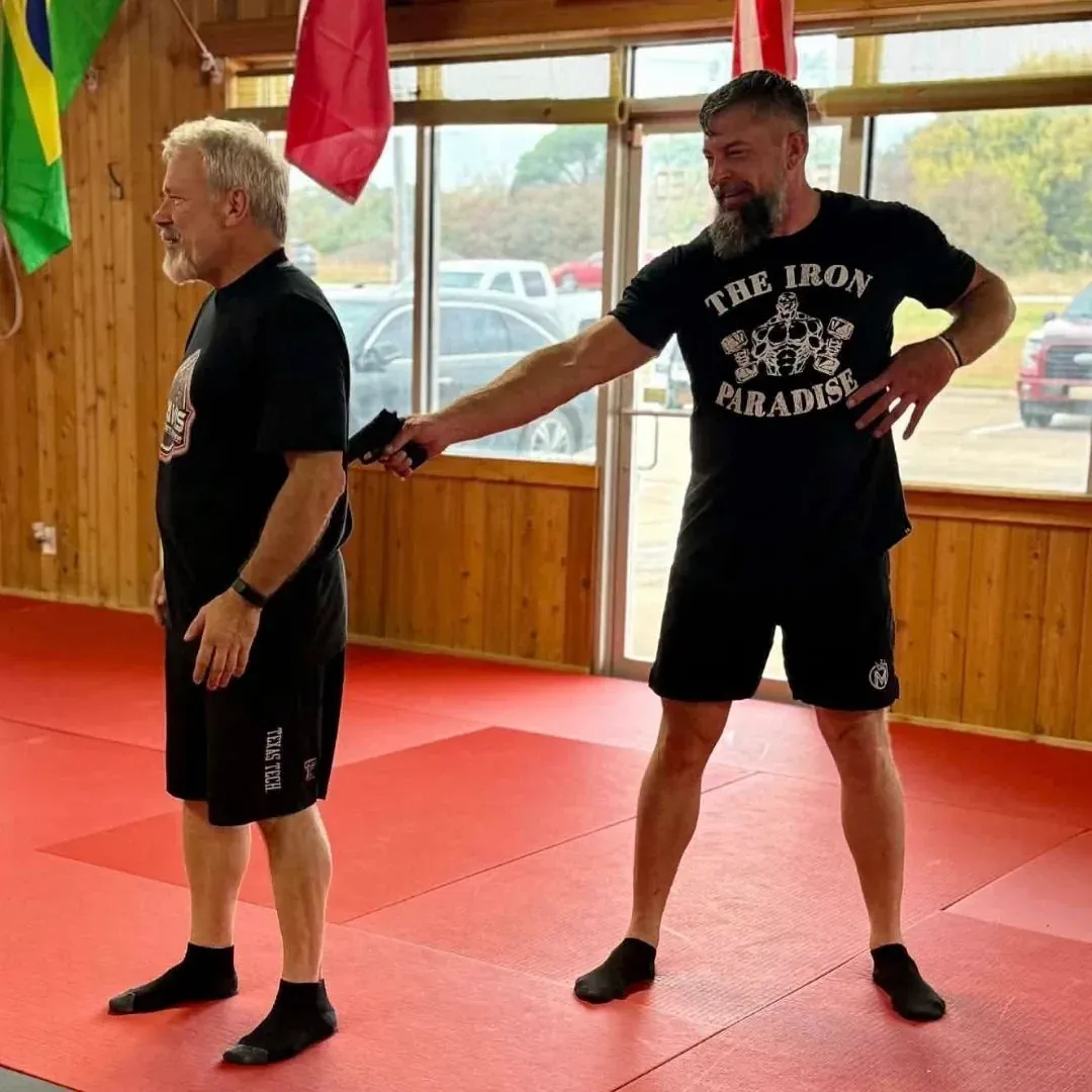 Two adults drilling a Krav Maga handgun-disarm self-defense technique at Davis Martial Arts & Fitness in Pilot Point, TX