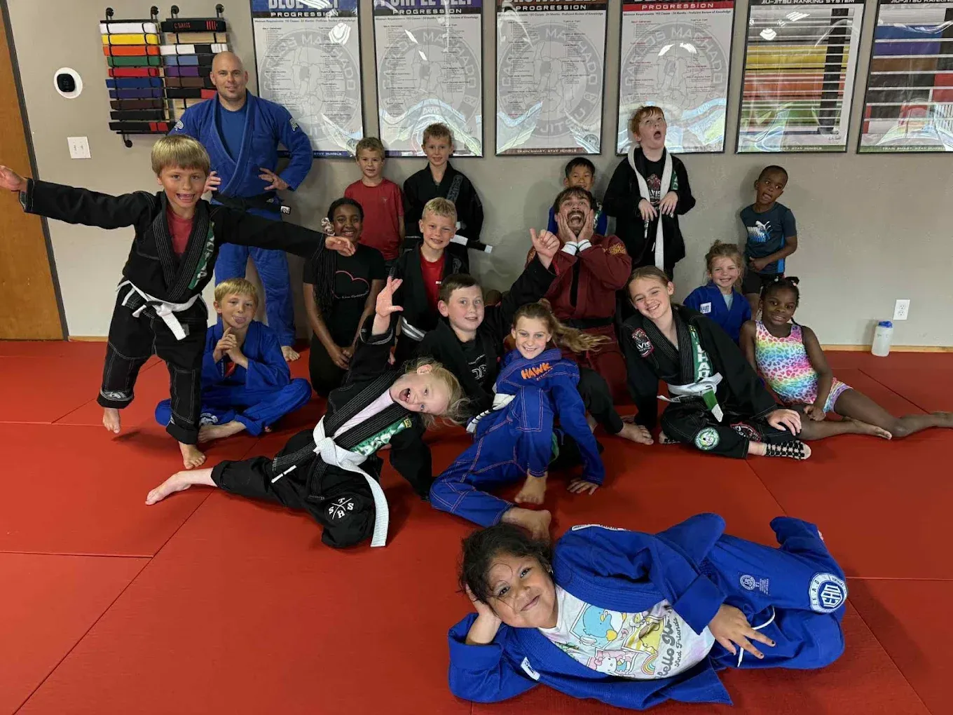 Kids in gis celebrating together on the mat with their coach after Brazilian Jiu-Jitsu class at Davis Martial Arts & Fitness in Pilot Point, TX