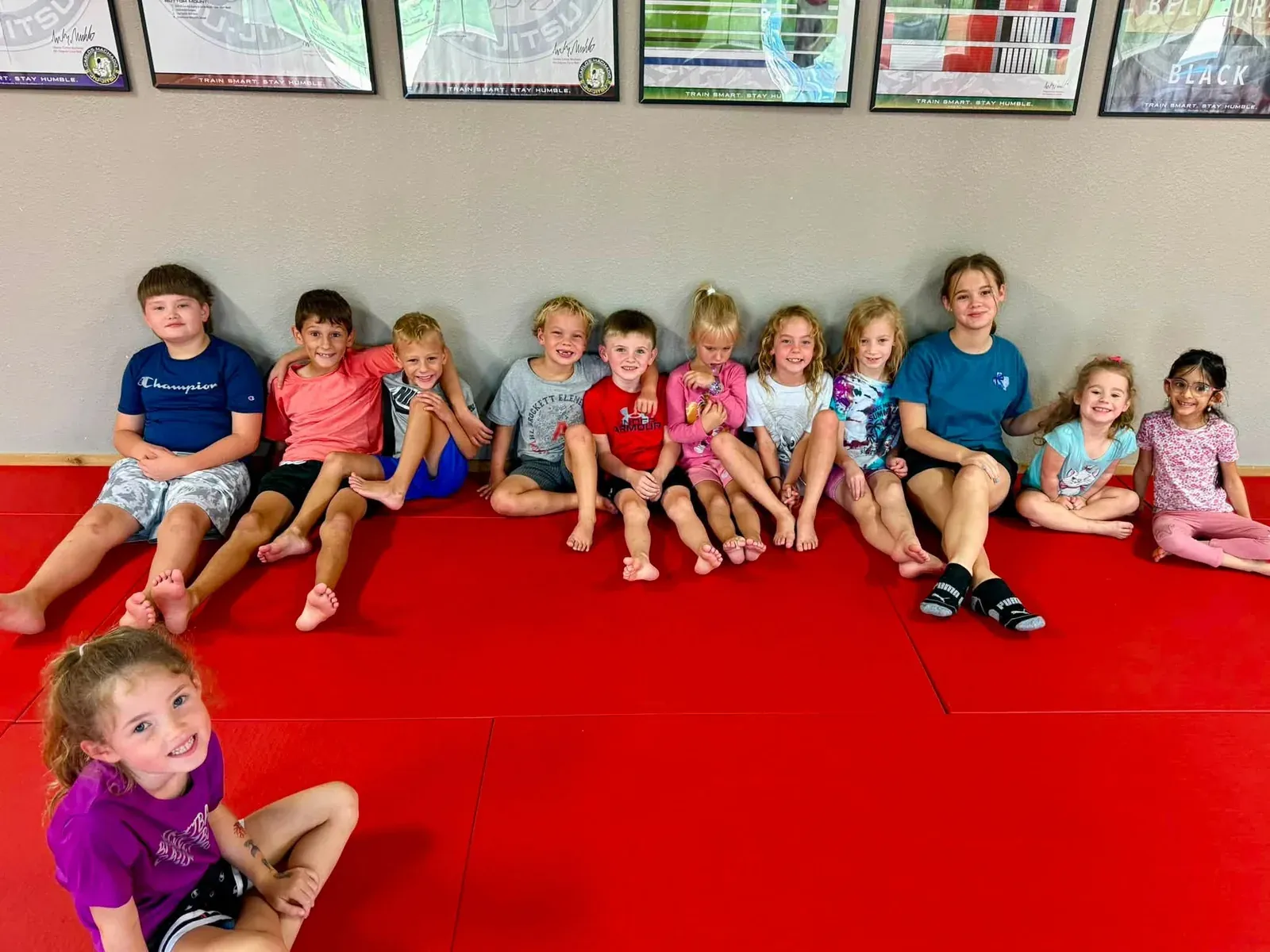Young students seated together along the mat before class at Davis Martial Arts & Fitness in Pilot Point, TX