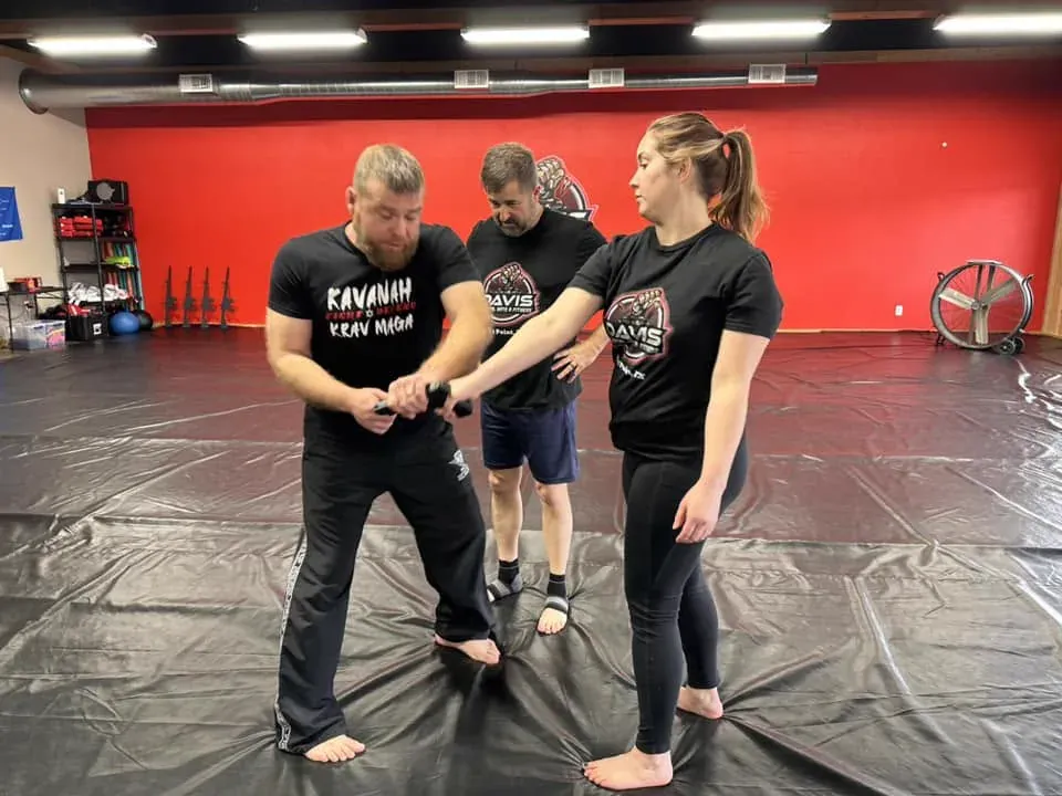 An instructor teaching a woman a wrist-lock escape during Krav Maga self-defense training at Davis Martial Arts & Fitness in Pilot Point, TX