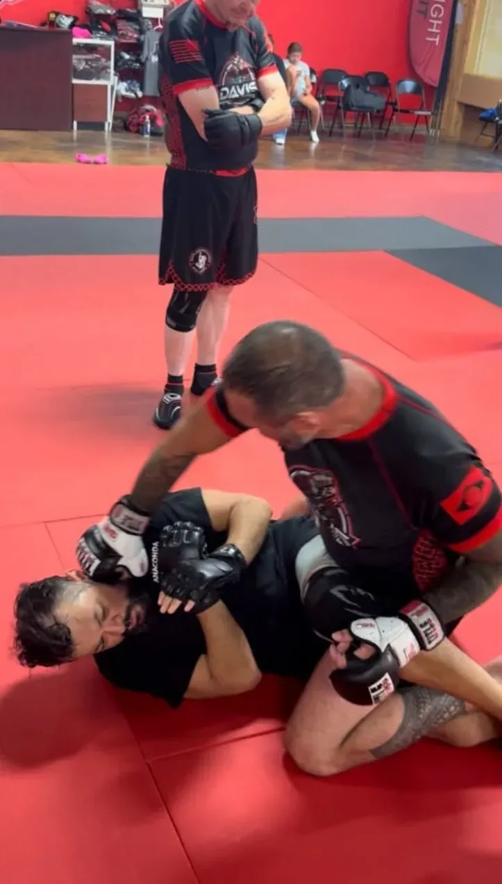 Two athletes in MMA gloves working from top position on the mat during MMA training at Davis Martial Arts & Fitness in Pilot Point, TX