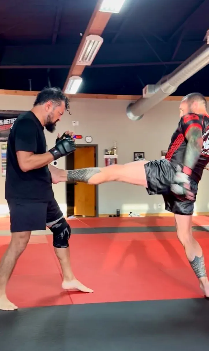 An athlete throwing a kick to a partner during MMA training at Davis Martial Arts & Fitness in Pilot Point, TX